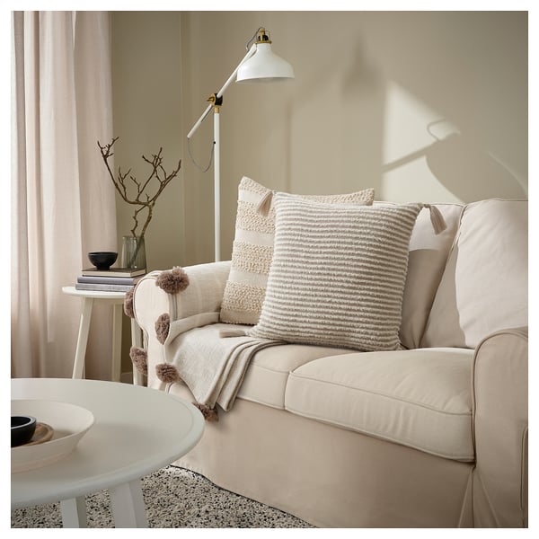 Espace de vie neutre avec canapé beige, housses de coussin tricotées et table basse ronde.