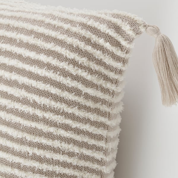 Housse de coussin rayée avec boucles blanches, couleur naturelle, texture douce, pompons au coin, tissu de qualité.