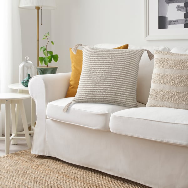 Salon confortable avec canapé blanc, coussin KRYPLJUNG et plantes.