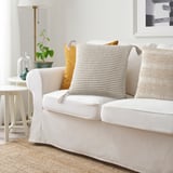 Salon confortable avec canapé blanc, coussin KRYPLJUNG et plantes.
