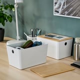Boîtes de rangement KUGGIS sur le bureau avec des écouteurs, des câbles, des stylos et des ciseaux.