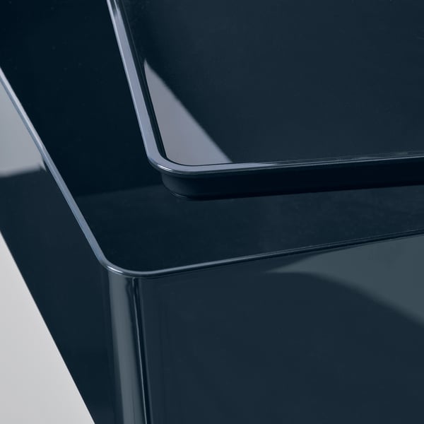 Boîte bleu foncé brillante avec couvercle, réfléchissant la lumière, mettant en valeur une surface lisse et des bords lisses.