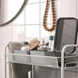 Support en métal avec savon et brosse à cheveux, miroir et carreaux.