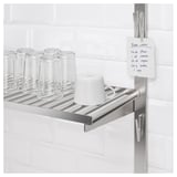 Étagère en métal dans la cuisine avec verres, tasse et note de recette fixée magnétiquement.