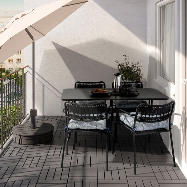 Set de table de balcon noir avec des chaises rembourrées et un parasol blanc.