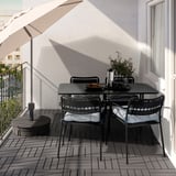 Set de table de balcon noir avec des chaises rembourrées et un parasol blanc.