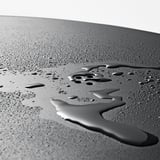 Gouttelettes d’eau sur une surface lisse, perlées, montrant un matériau hydrophobe.