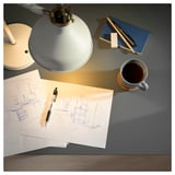 Configuration du bureau de travail avec lampe, croquis, stylo, cahier et café.