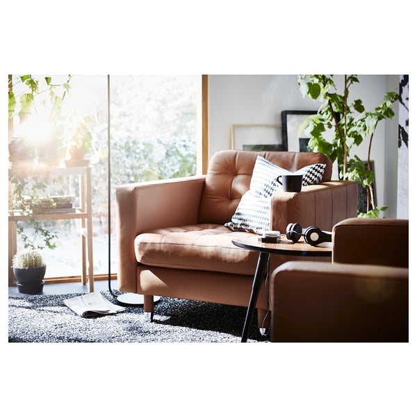 Un salon cosy avec un fauteuil en cuir marron, une table d’appoint et des plantes.