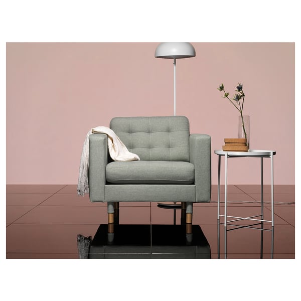 Salon moderne avec fauteuil LANDSKRONA gris, table d’appoint et lampadaire contre des murs roses.