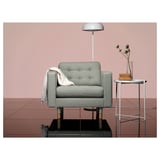 Salon moderne avec fauteuil LANDSKRONA gris, table d’appoint et lampadaire contre des murs roses.