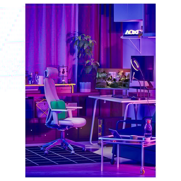 Une configuration de bureau de jeu colorée avec une chaise ergonomique LÅNESPELARE en vert, des écrans d’ordinateur, des néons et des plantes.
