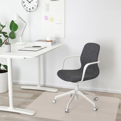 Bureau à domicile minimaliste : bureau, horloge, plante, chaise ergonomique.