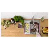 Vue de dessus d’un comptoir de cuisine en bois avec évier en acier inoxydable ; Assortiment de légumes et ustensiles de cuisine soigneusement rangés.