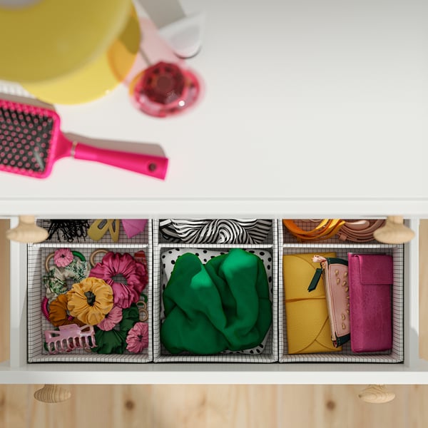 Tiroir organisé en trois sections : accessoires colorés pour les cheveux, chaussettes vertes et petits vêtements pliés.