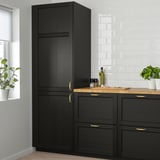 Armoire de cuisine noire avec cadre en bois massif et panneaux de placage, poignées dorées, verdure.