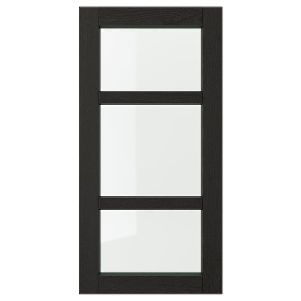 Une porte d’armoire de cuisine LERHYTTAN noire avec un cadre en bois massif et des panneaux en verre transparent, mettant en valeur un design traditionnel.