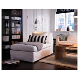 Salon moderne avec un lampadaire LERSTA blanc, doté d’une chaise à rayures noires et blanches, d’une table basse en bois, d’un tapis confortable et d’une étagère.