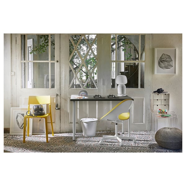 Configuration de bureau moderne avec table et chaise LINNMON jaunes, grande fenêtre, bureau avec ordinateur portable et tiroir de rangement.