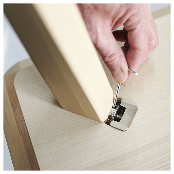 La personne assemble des meubles en bois clair. Produit : LISABO. Design moderne et minimaliste.