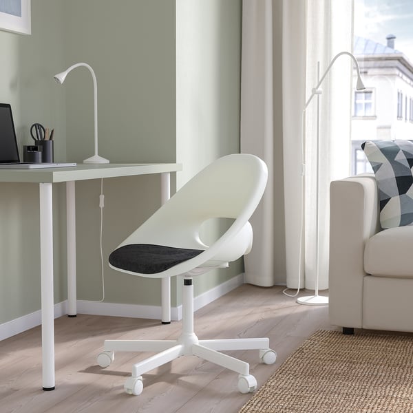 Chaise de bureau blanche au bureau avec lampes, canapé et tapis.