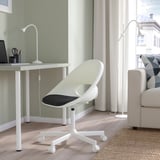 Chaise de bureau blanche au bureau avec lampes, canapé et tapis.