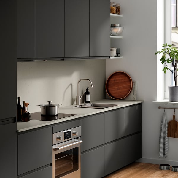 Cuisine moderne avec plan de travail en verre gris recyclé, évier et placards sombres.