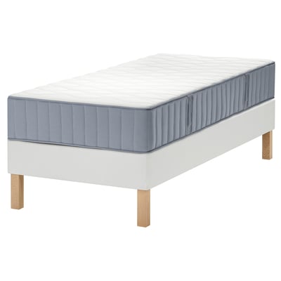 Un lit LYNGÖR avec un sommier blanc et un matelas gris clair. Il a des pieds en bois et une surface de matelas matelassée et texturée.