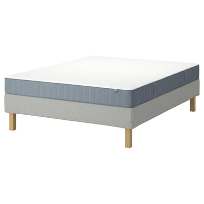 Un sommier LYNGÖR avec un matelas vesteröy. La base du lit est gris clair et en bois, soutenant un matelas blanc et bleu avec un drap-housse.