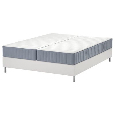 Combo sommier et matelas LYNGÖR. A une base blanche, une bordure grise, quatre pattes. Le matelas dispose de cinq zones de confort.