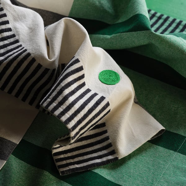 Des rideaux rayés verts et blancs, tissés avec un savoir-faire minutieux, sont élégamment suspendus.