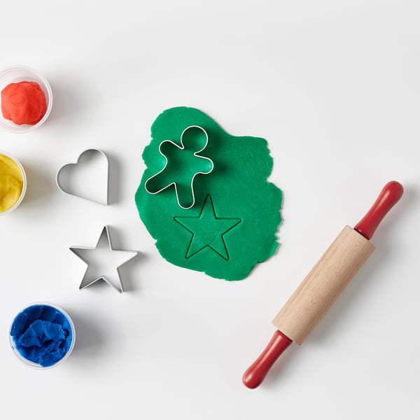 Un ensemble de bricolage composé de pâte verte, d’emporte-pièces en métal et d’un rouleau à pâtisserie.
