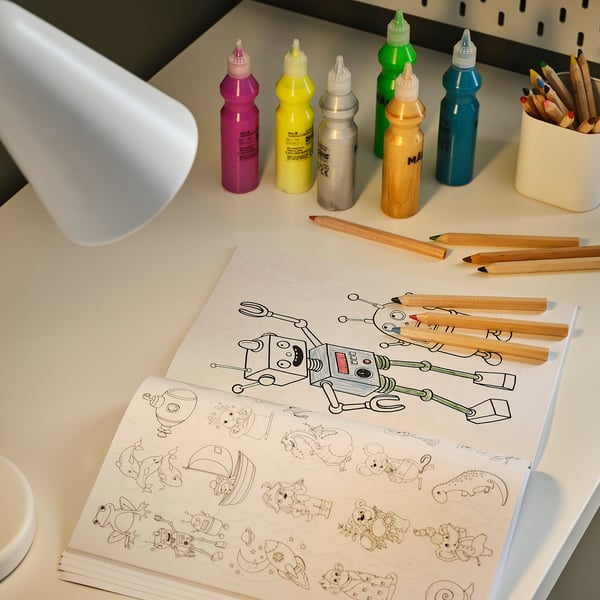 Bureau coloré avec des fournitures d’art et une lampe éclairant un livre de coloriage de robot.