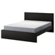 Lit minimaliste en bois noir avec matelas gris, tête de lit haute, design élégant.