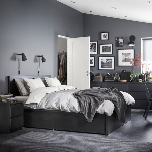 Chambre moderne avec des murs gris foncé, un lit MALM noir avec des draps blancs, des tables de chevet et un mur de photos en noir et blanc.