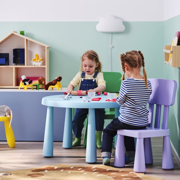Deux jeunes filles jouant avec des jouets sur une table colorée et légère à roulettes.