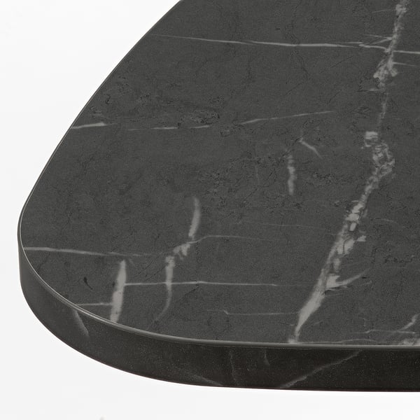 Gros plan d’une table d’appoint moderne avec un dessus de table élégant et sombre, présentant une finition lisse et mate et des veines subtiles.