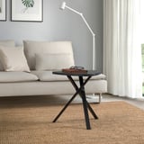Salon moderne avec canapé blanc, petite table d’appoint MARIEDAMM en noir, plateau rectangulaire, pieds entrecroisés, près de la fenêtre.