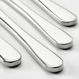 Quatre couteaux élégants et polis en acier inoxydable disposés soigneusement en rangée, mettant en valeur leurs lames tranchantes et réfléchissantes.