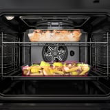 Four à convection cuisant plusieurs plats. L’étagère supérieure a un plat cuit, inférieure a des légumes.