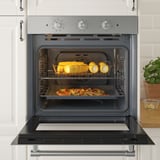 Four en acier inoxydable à convection forcée par ventilateur, cuisant plusieurs plats uniformément ; visible avec plateau de maïs et d’ananas.