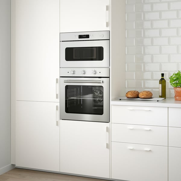 Cuisine moderne avec four en acier inoxydable MATTRADITION et micro-ondes combo entre les armoires blanches.