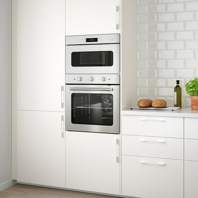 Cuisine moderne avec four en acier inoxydable MATTRADITION et micro-ondes combo entre les armoires blanches.