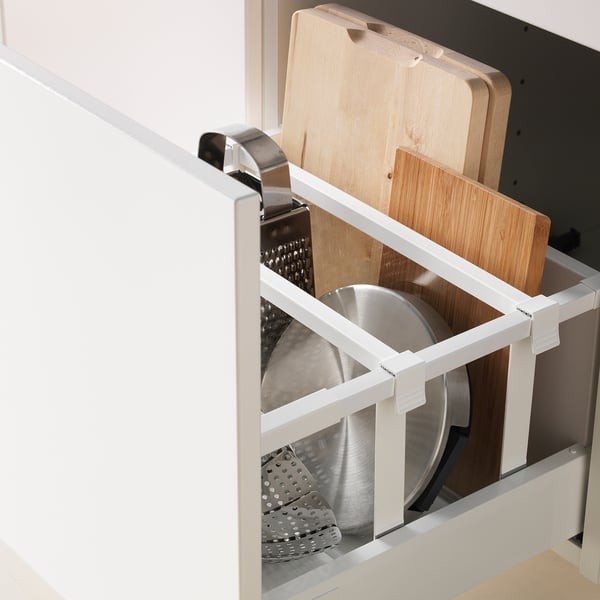 Le tiroir de cuisine blanc s’est complètement retiré, contenant des passoires en métal et des planches à découper en bois, démontrant son extension et son organisation complètes.