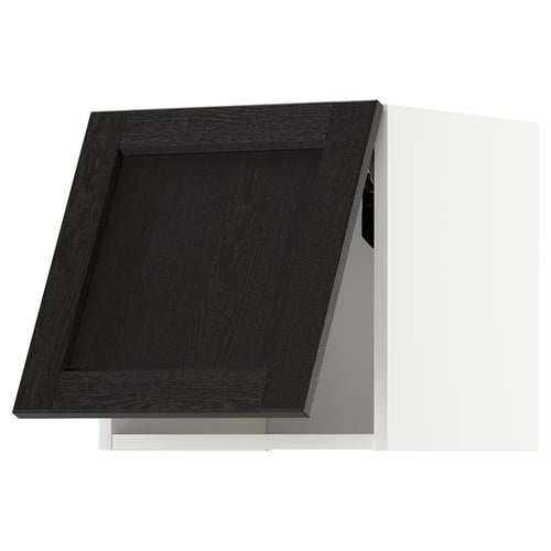 Armoire de cuisine noire au design traditionnel, en bois teinté. Une seule porte aux bords biseautés, adossée à un mur blanc.