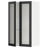 Une armoire murale de cuisine METOD blanche avec une porte en verre hejsta noir avec verre cannelé et cadres en métal avec poignées intégrées.