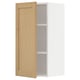 Présente une armoire murale de cuisine METOD blanche avec une seule porte en bois ouverte, avec un placage de chêne et des bords biseautés.