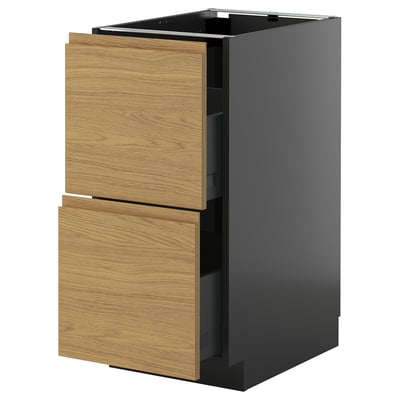 Un meuble de cuisine moderne appelé METOD avec une base gris foncé et des tiroirs en bois effet chêne avec des poignées minimalistes.