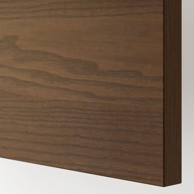 Un gros plan d’un bord d’armoire en bois, mettant en valeur la qualité du placage de frêne teinté brun foncé avec une texture de grain de bois visible.