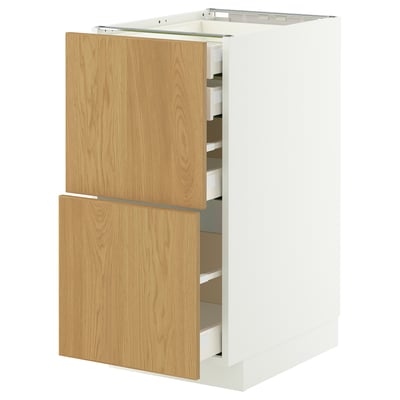 Armoire de cuisine METOD blanche avec tiroirs en chêne clair, partiellement ouverte montrant un intérieur organisé. Tiroirs à fermeture automatique.